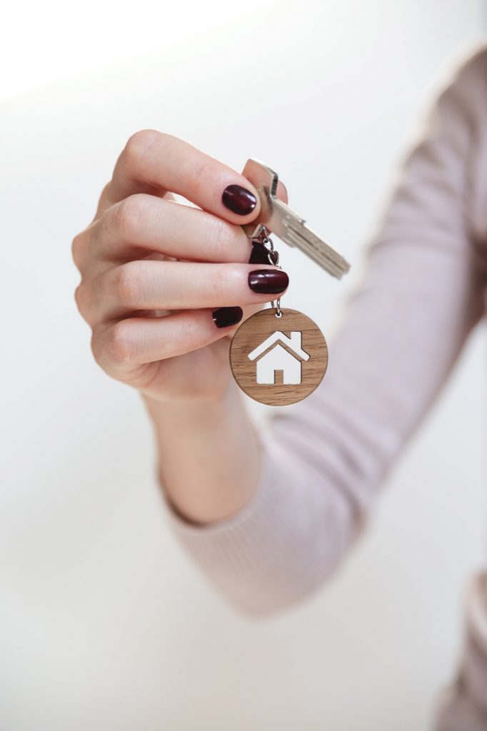 Real estate concept. Keys with a house shaped keychain in a woman's hand.